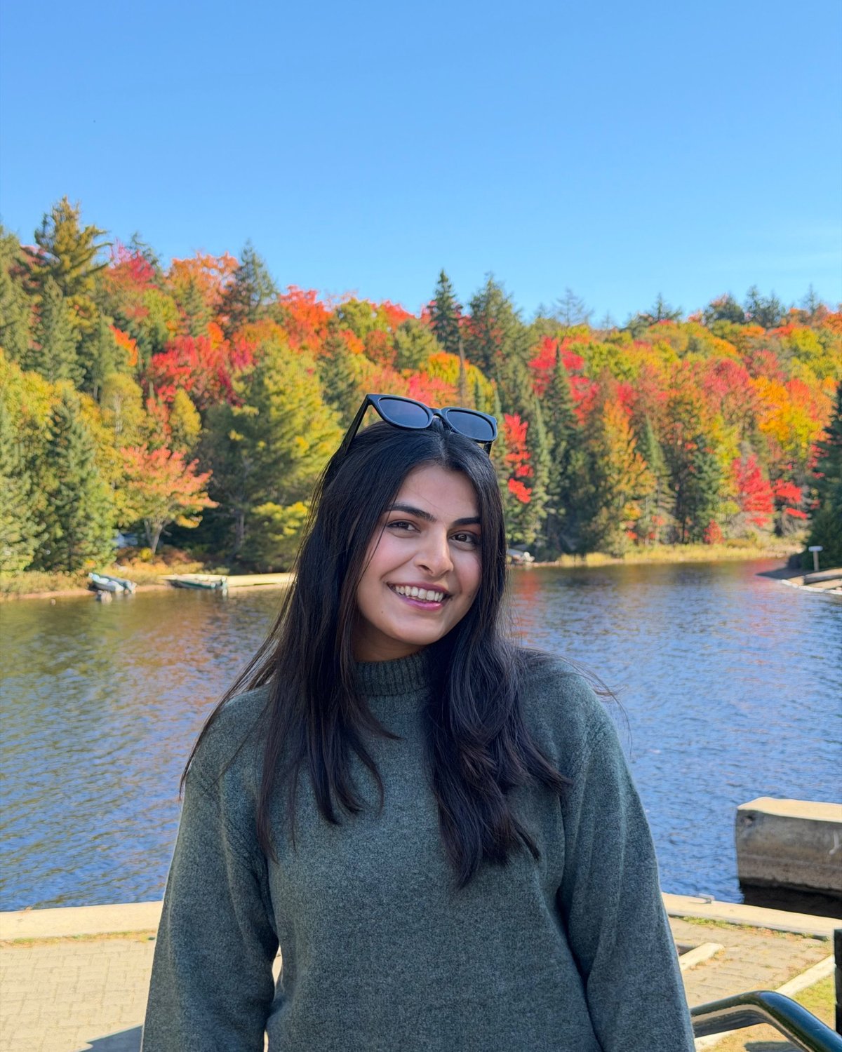 Arooj Fatima smiling by a lake framed by autumn trees